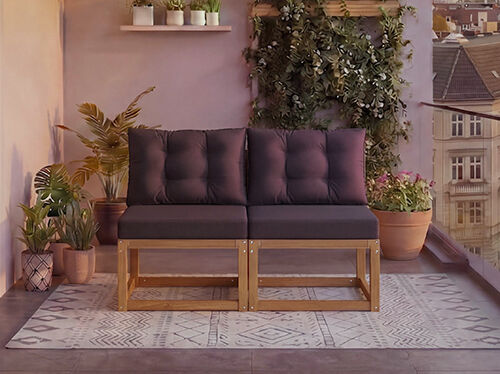 Dwuosobowa modularna drewniana sofa z ciemnoszarymi poduszkami na balkonie otoczonym doniczkowymi roślinami i widokiem na miasto w tle