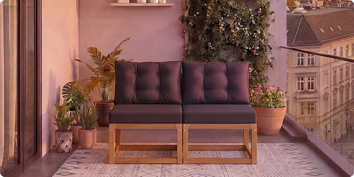  Dwuosobowa modularna drewniana sofa z ciemnoszarymi poduszkami na balkonie otoczonym doniczkowymi roślinami i widokiem na miasto w tle