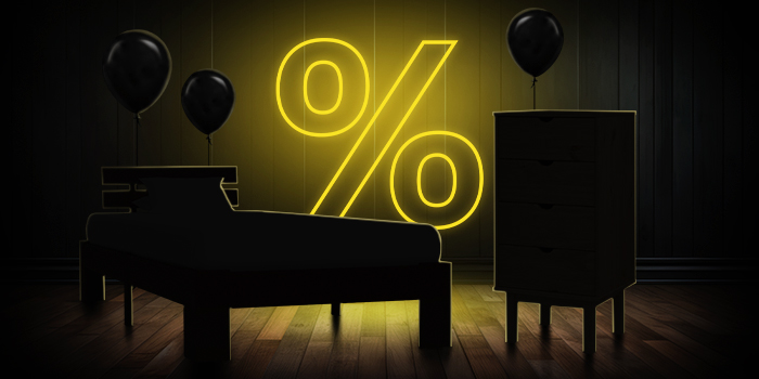 Czarne łóżko i komoda z czarnymi balonami przed jasnożółtym znakiem procentu na ciemnej drewnianej podłodze.